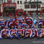 Moulin Rouge dancers pose with a Tour de France display in front of the famous Paris cabaret.