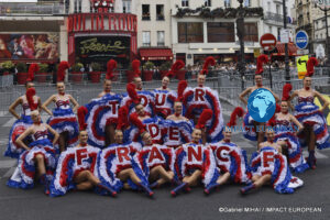 Moulin Rouge dancers pose with a Tour de France display in front of the famous Paris cabaret.