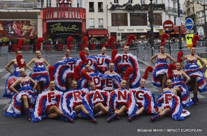 Moulin Rouge dancers pose with a Tour de France display in front of the famous Paris cabaret.