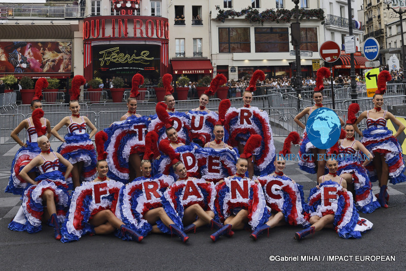 Moulin Rouge dancers pose with a Tour de France display in front of the famous Paris cabaret.